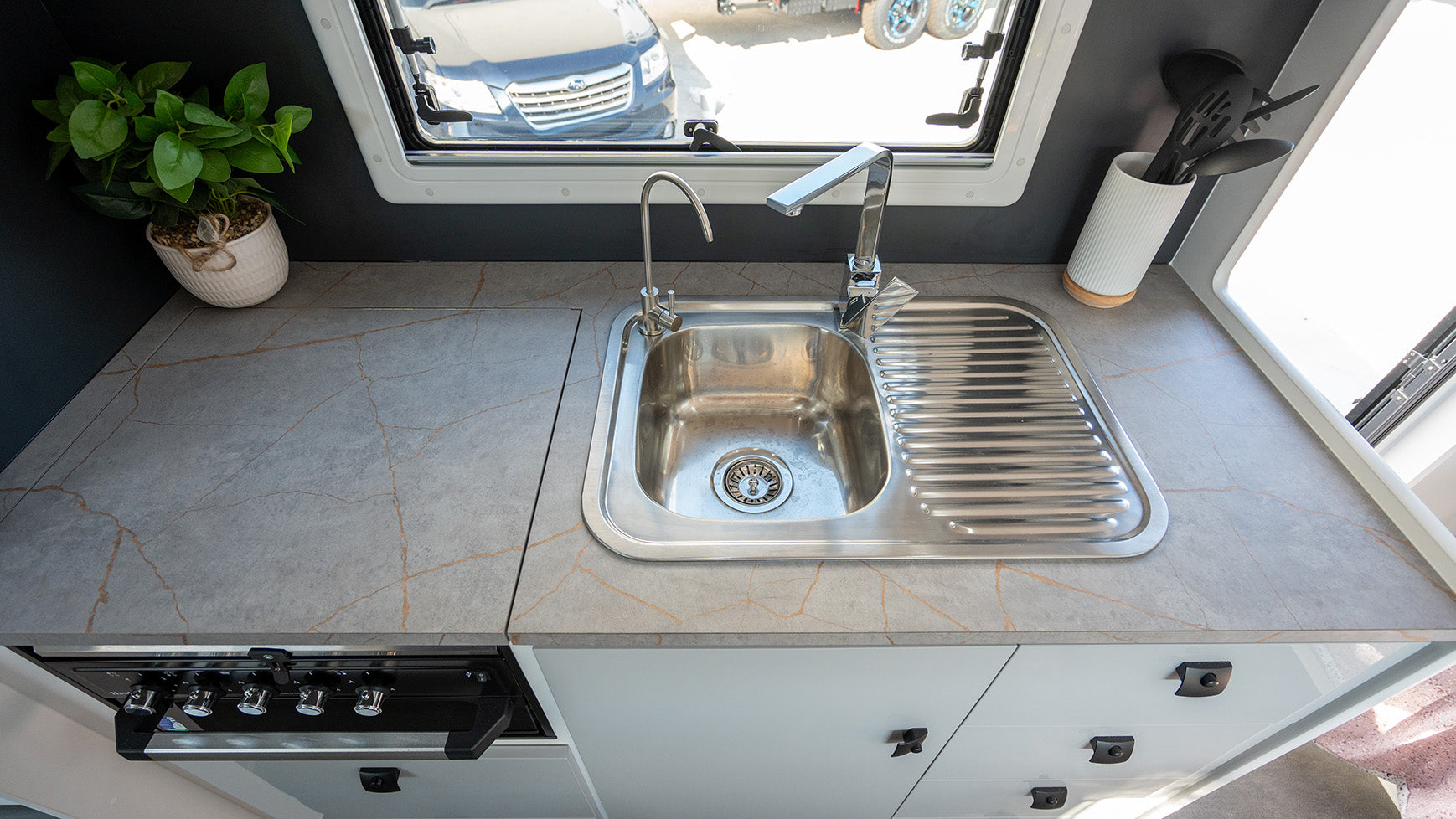 ProRV Family Hawk Caravan Interior Kitchen Including Tap, Sink, Covered Cooktop, Drawers, and Oven.