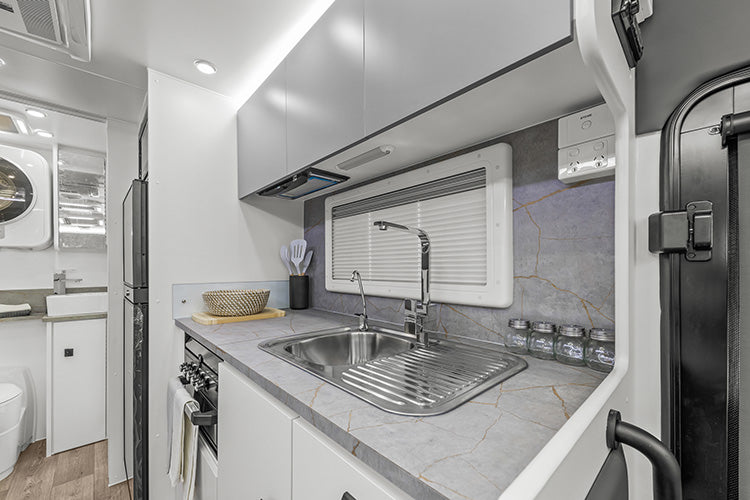ProRV Family Jaguar Caravan Interior Kitchen Including Tap, Sink, Covered Cooktop, Cupboards, Drawers, and Oven Angled.