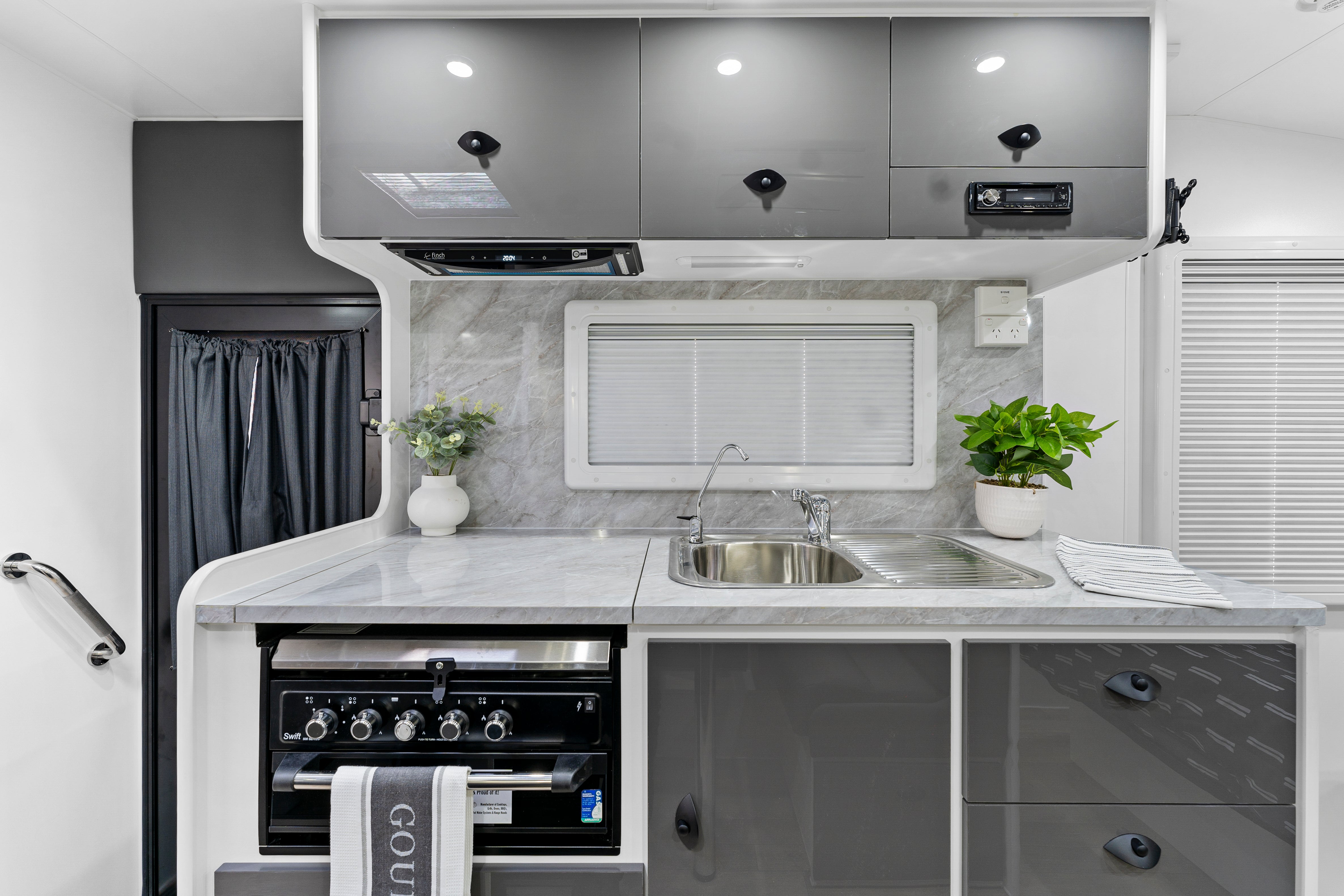 ProRV Jaguar Caravan Interior Kitchen Including Tap, Sink, Covered Cooktop, Cupboards, Drawers, and Oven Zoomed Out.